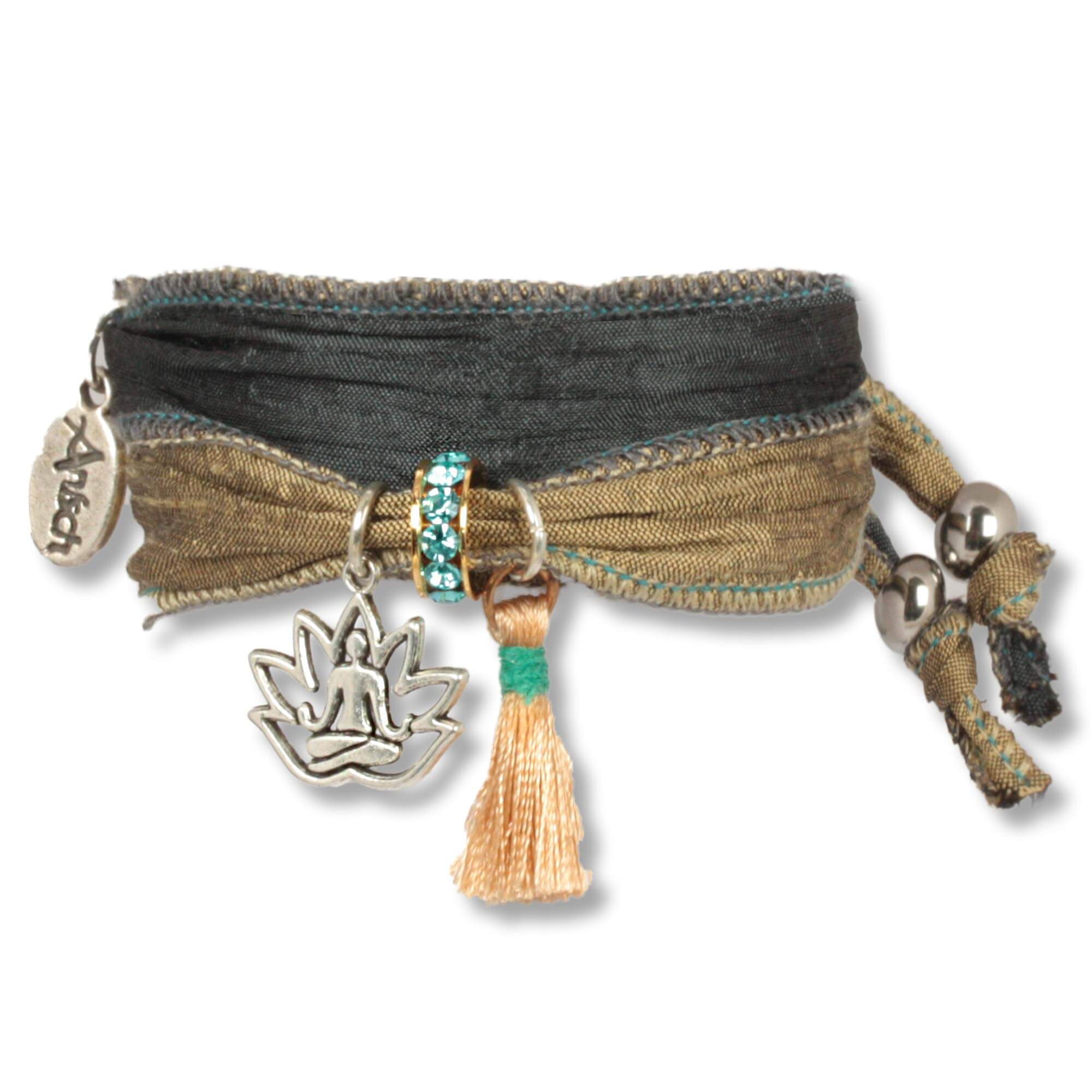 Handmade fabric bracelet made from saris and silk fabrics in olive green and Anthracite colours. Decorated with a metal lotus flower depicting a meditating Buddha, a rosé silk tassel and a rondel set with Czech crystals. Anísch